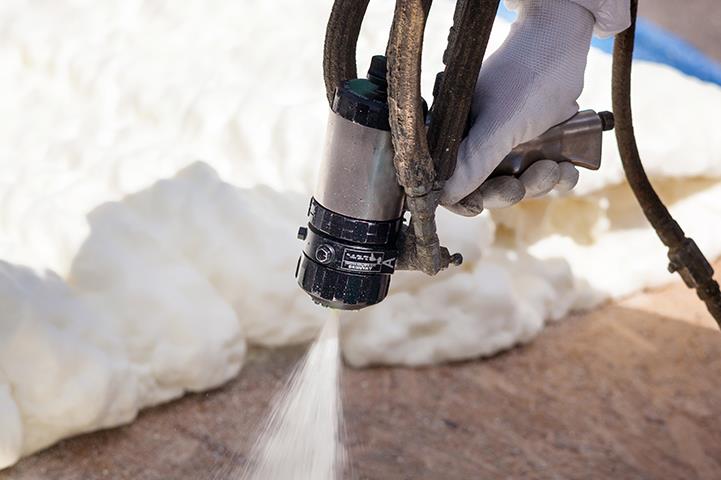 closeup of hand holding foam insulation sprayer spraying foam