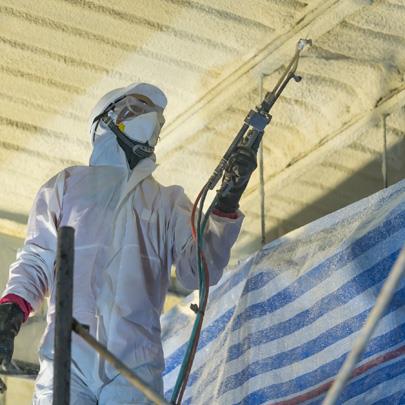 person in safety gear spraying foam